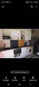聖母山的住宿－Appartement bord de mer，厨房配有白色橱柜和黑色家电