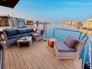 une terrasse en bois avec des canapés et des tables sur un bateau dans l'établissement Hausboot inkl Motorboot, Ostsee, à Heiligenhafen