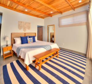 1 dormitorio con cama y banco. en Casa Ojos Azules, Nosara. New Listing, en Nosara