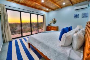 een slaapkamer met een bed en een groot raam bij Casa Ojos Azules, Nosara. New Listing in Nosara +26 foto's