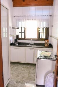 eine Küche mit weißen Schränken, einem Waschbecken und einem Fenster in der Unterkunft Chacara com churrasq, piscina e lazer - Socorro SP in Socorro