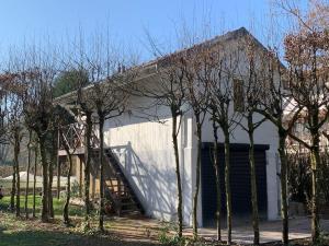 a white building with a garage and some trees at chalet paradisiaque en bord de Marne Proche de Disneyland in Isles-lès-Villenoy