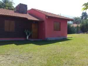 una pequeña casa roja con un patio verde en Solares de Cacheuta en Cacheuta