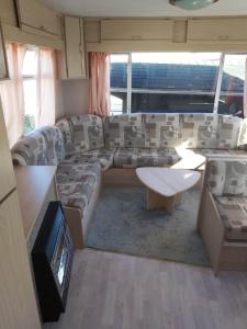 salon z kanapą i stołem w obiekcie Caravan 2 bedroom - New Camping Ideal w mieście De Haan