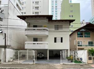 een wit huis met een hek ervoor bij Dambroso Residence in Balneário Camboriú