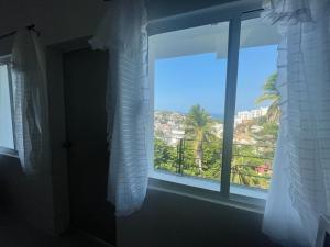 a window with a view of a palm tree at 208 in Acapulco