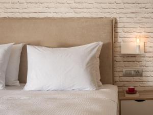 a bed with white pillows and a table with a lamp at Unique seaside apartment in Rethymno Town