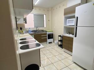 cocina con nevera blanca y fregadero en Dambroso Residence, en Balneário Camboriú
