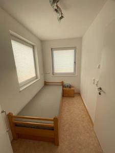 een lege kamer met een bed en twee ramen bij Karo`s Apartment in Mittersill