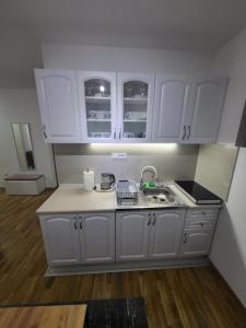 a kitchen with white cabinets and a sink at FoRest apartment & spa in Zlatibor