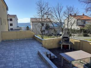 a patio with a grill and a table and a bench at Apartman Bonaca in Jadranovo