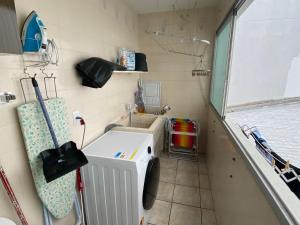 een kleine badkamer met een wasmachine en een wastafel bij Dambroso Residence in Balneário Camboriú