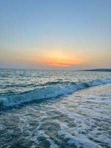 una playa con el océano y la puesta de sol en el fondo en Le Solite Holiday Rooms en SantʼEufemia Lamezia
