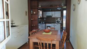 cocina con mesa de madera y algunas sillas en Casa con jardín en la playa de Almieiras en Fene
