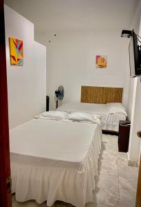 2 letti in una camera con pareti bianche di CASA SHILCAYO Habitaciones Vacacionales a Tarapoto