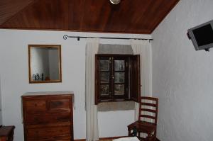 a room with a window and a dresser and a television at Casa da Janal in Vimioso