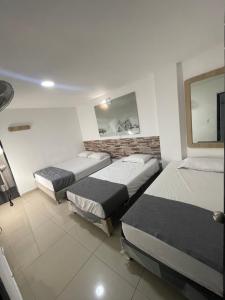 Habitación con 3 camas y TV. en HOTEL SELECT en Medellín