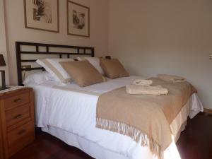a bedroom with a bed with white sheets and a dresser at Las Palmeras in Caldas de Reis