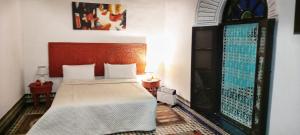 een slaapkamer met een bed met een houten hoofdeinde bij Palais AL Firdaous Medina in Fès al Bali