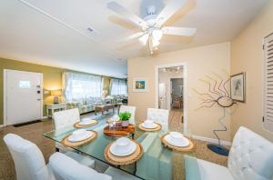 a dining room with a glass table and white chairs at Sunset Beach House in Clearwater Beach