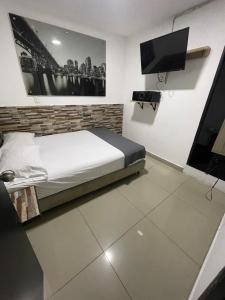 a bedroom with a bed and a flat screen tv at HOTEL SELECT in Medellín