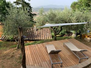 una terraza con 2 sillas y una sombrilla blanca en La Casa sui Colli, en Uzzano