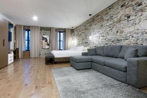 sala de estar con sofá y pared de piedra en La Maison Kent - Par Les Lofts Vieux-Québec en Quebec