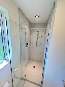 a shower with a glass door in a bathroom at Be My Guest in Beachlands in Auckland