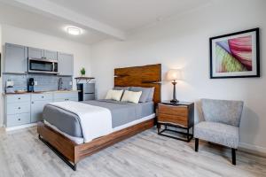 a bedroom with a bed and a chair and a kitchen at Unit 16 Maui Ohana Modern Studio in Wailuku