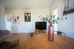 - un salon avec une table et un vase fleuri dans l'établissement Apartament Glorieta Puerta de Toledo, à Madrid