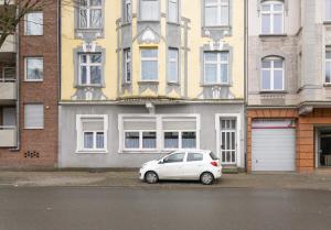 un coche blanco estacionado frente a un edificio en T&K Apartments - Duisburg - 4 Rooms Apartment - 2nd Floor en Duisburg