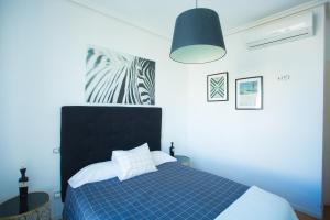 sypialnia z niebieskim łóżkiem z czarnym zagłówkiem w obiekcie Apartament Glorieta Puerta de Toledo w Madrycie
