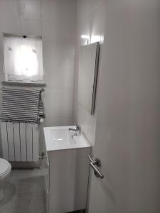 a white bathroom with a sink and a toilet at Casa do Serrinho in Seia