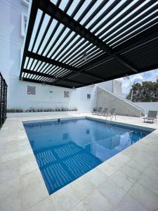 an indoor swimming pool with awning and a patio at Fato Hotel in Querétaro