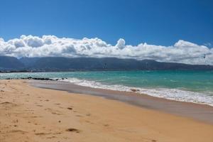 a beach with the ocean and mountains in the background at Unit 17 Maui Ohana Modern Studio in Wailuku