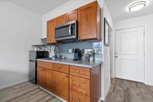 a kitchen with wooden cabinets and a microwave at Unit 17 Maui Ohana Modern Studio in Wailuku