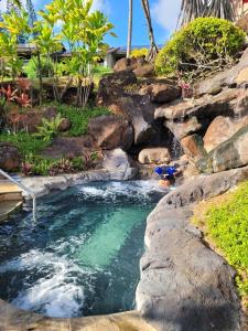 a swimming pool with a waterfall in a backyard at Hanalei Bay Resort BaliHi in Princeville