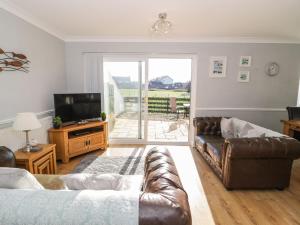 a living room with a couch and a television at Beach House Ty Traeth in Deganwy