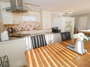 a kitchen with a wooden table with a vase of flowers on it at Beach House Ty Traeth in Deganwy