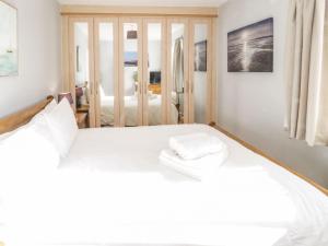 een slaapkamer met een wit bed en 2 handdoeken bij Beach House Ty Traeth in Deganwy