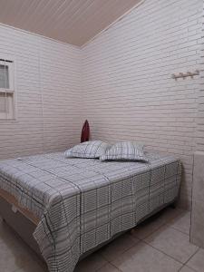 Ce lit se trouve dans une chambre dotée d'un mur en briques. dans l'établissement Casa Moita, Linda Casa, Muito Central, Hospeda até 9 ou 12 Pessoas, à Rio Grande