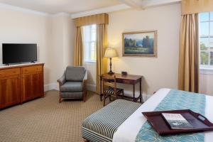 Habitación de hotel con cama, escritorio y TV. en Historic Boone Tavern, en Berea