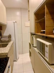 a white kitchen with a sink and a refrigerator at Apto moderno e bem localizado in Recife