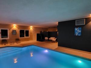 a large swimming pool in a room with a living room at Beddy-bye Hôtel in Contrexéville