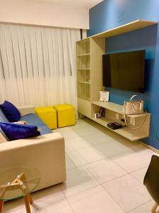 uma sala de estar com um sofá e uma televisão de ecrã plano em Apto moderno e bem localizado no Recife