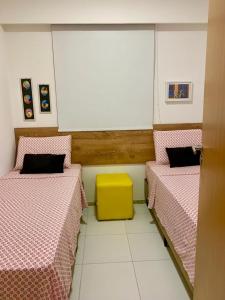 um quarto com duas camas e uma mesa amarela em Apto moderno e bem localizado no Recife