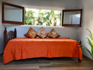a bed with an orange blanket and two windows at Chalet Pura Vida in Mar del Plata
