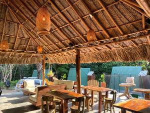 een patio met tafels en stoelen onder een rieten parasol bij Sierra Jungla in Minca