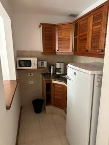 a small kitchen with a white refrigerator and wooden cabinets at Hotel Club de La Barra in Punta del Este