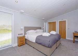 1 dormitorio con 1 cama con 2 almohadas en Luxury 5 Star London Lodge - Parking, Garden, Hot Tub, near Metro Stations, en Wallington